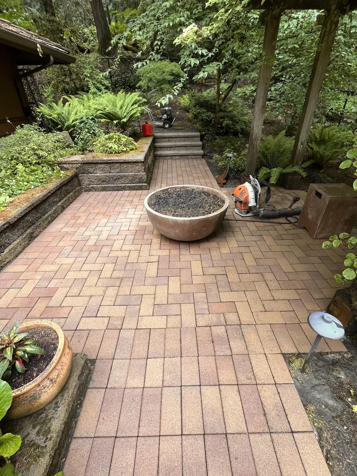 Herringbone brick patio around a fire pit, washed back to clean warm pavers — our work